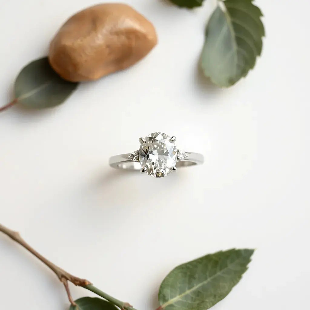 Oval-cut diamond ring with a polished band on a neutral background under soft light