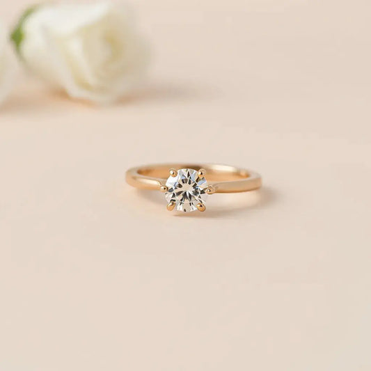 A classic solitaire engagement ring with a round diamond and simple four-prong setting on a soft neutral background