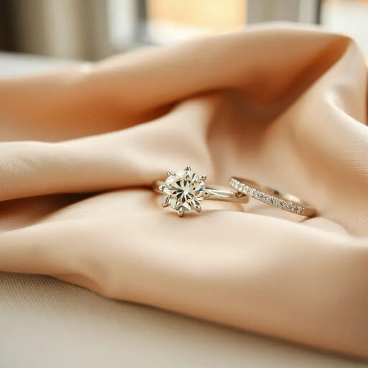 Elegant solitaire engagement ring with diamond sparkle and a matching band on neutral satin fabric