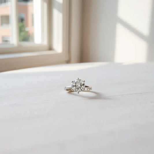 Solitaire diamond engagement ring with soft neutral background and natural window lighting