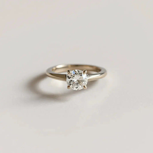Modern diamond ring with a brilliant-cut stone in a sleek geometric setting on a neutral background