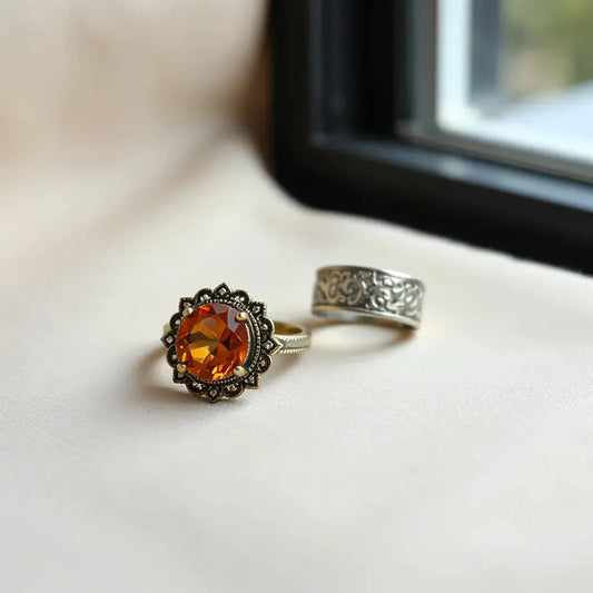 Ornate vintage style rings with warm gemstone and filigree details on a neutral background