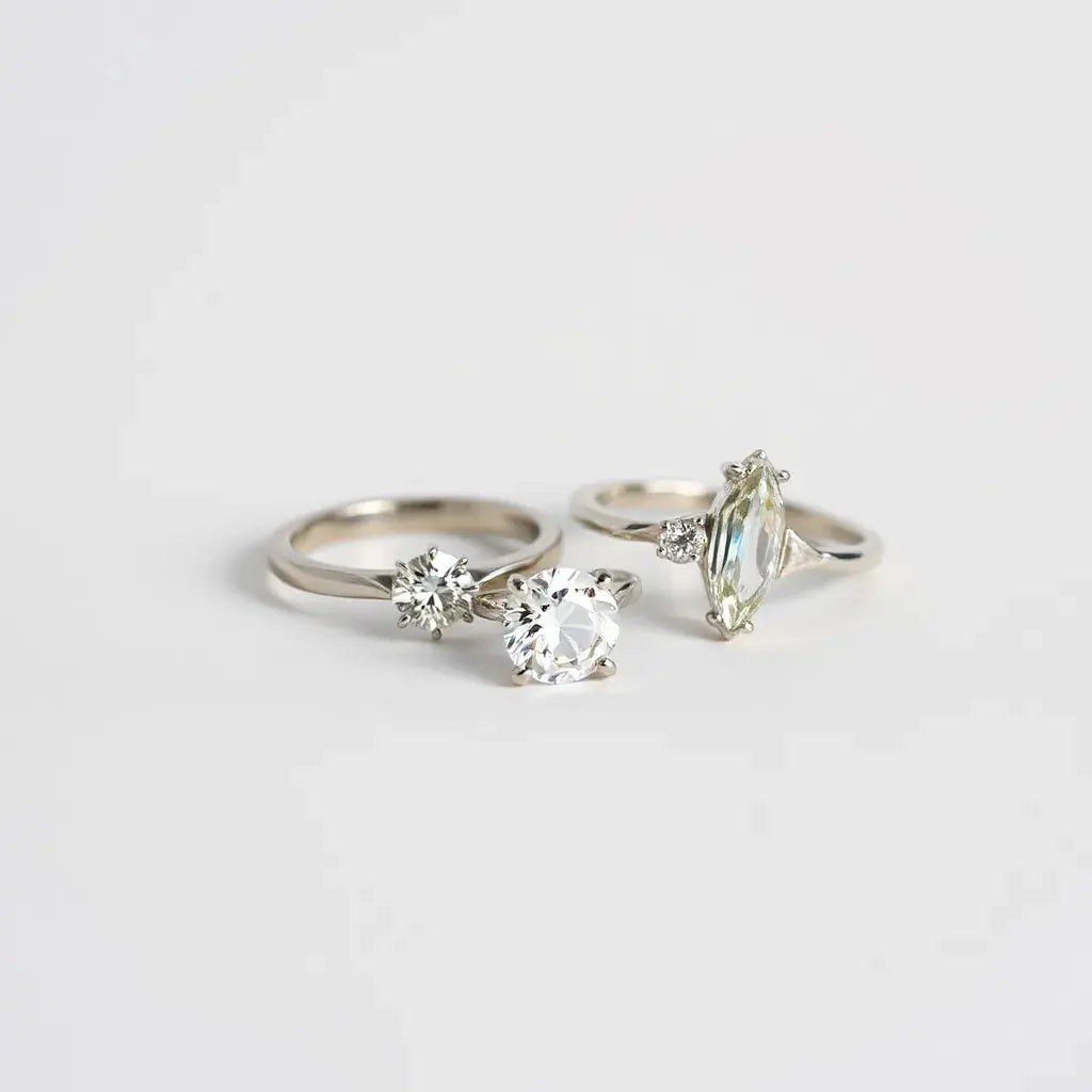 Two lab-grown diamond rings on a neutral background, showing the solitaire and halo stone settings