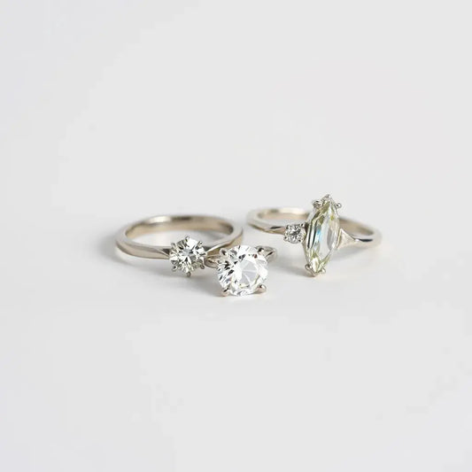 Two lab-grown diamond rings on a neutral background, showing the solitaire and halo stone settings