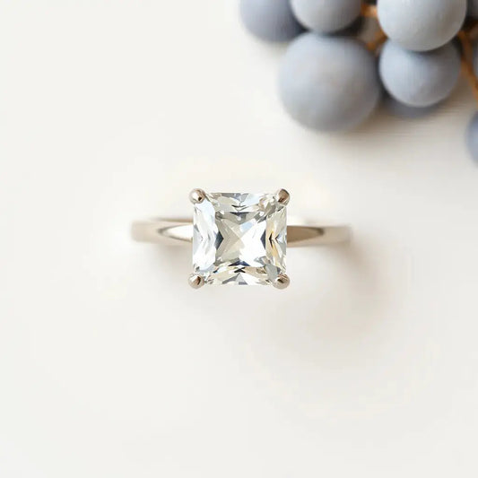 Princess cut diamond ring with square facets and a delicate band on a light neutral background