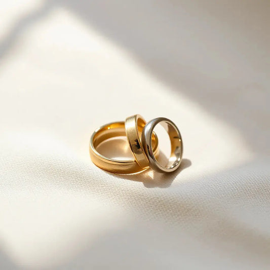 Two polished luxury wedding bands on neutral fabric with soft natural light and subtle reflections