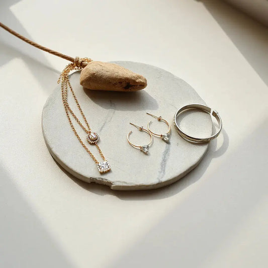 Layered necklaces, hoop earrings, and a delicate bracelet displayed in soft natural light