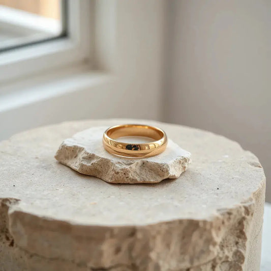 Polished 14k solid gold ring on a neutral stone surface with soft studio lighting